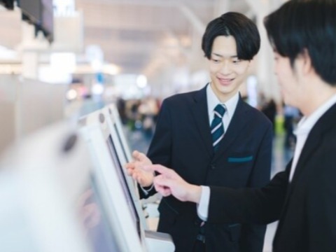 空港でチェックイン機械の案内をしている男性グランドスタッフ