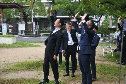 上空を飛行するドローンに手を振る、藪本支店長（右）と尾花和歌山市長（左）